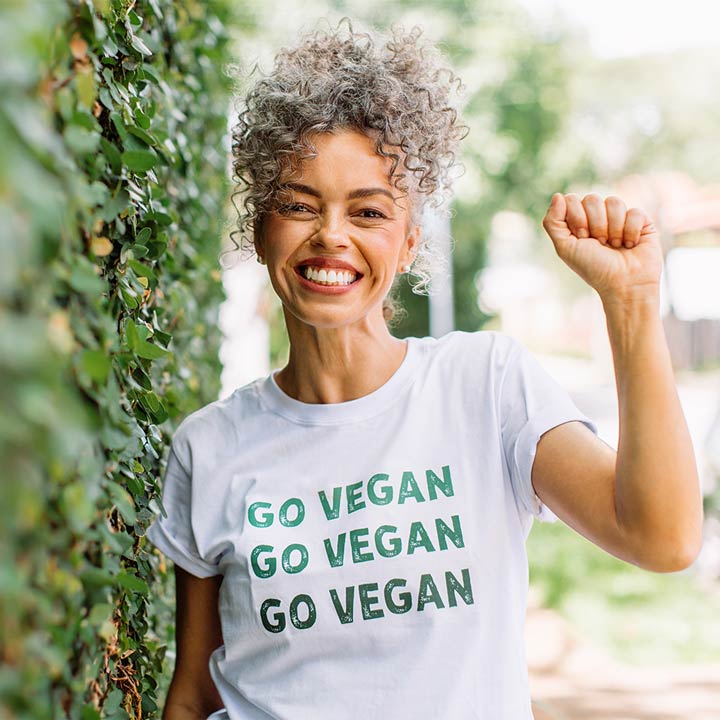 Thema – Vegane Ernährung Eine Frau trägt ein T-Shirt mit dem Aufdruck "Go Vegan" und hebt die geballte Hand.