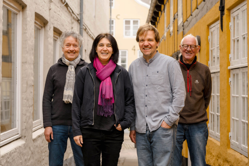 Das Bild zeigt das Team der Flensburger Hofkultur, in einer historischen Gasse der Altstadt stehend. Darauf zu sehen sind der Vorstand Joachim Pohl, Vicky Richter, Thomas Frahm und Geschäftsführer Gunnar Astrup.